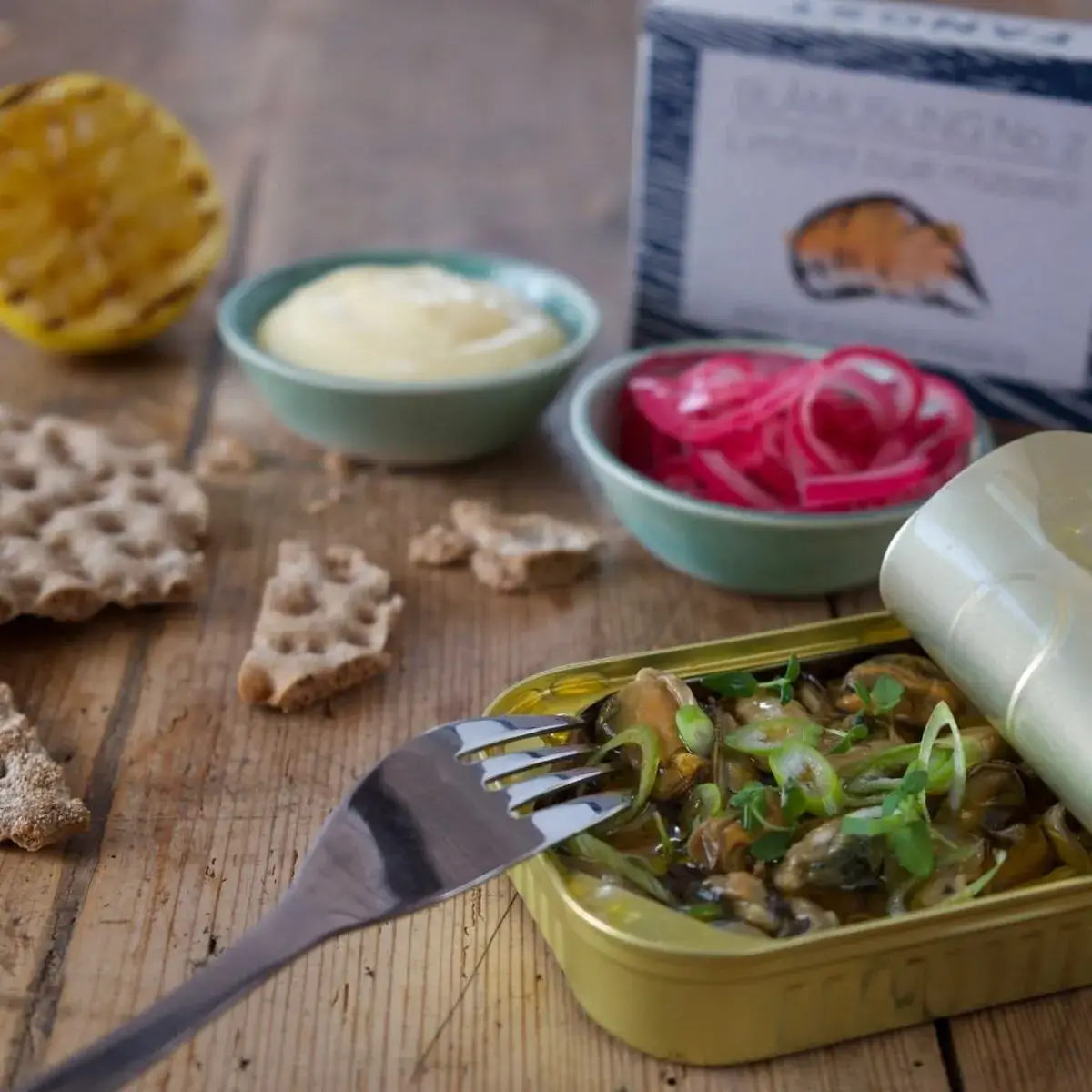 Open blik gerookte mosselen met crackers, mayo en ingelegde rode ui